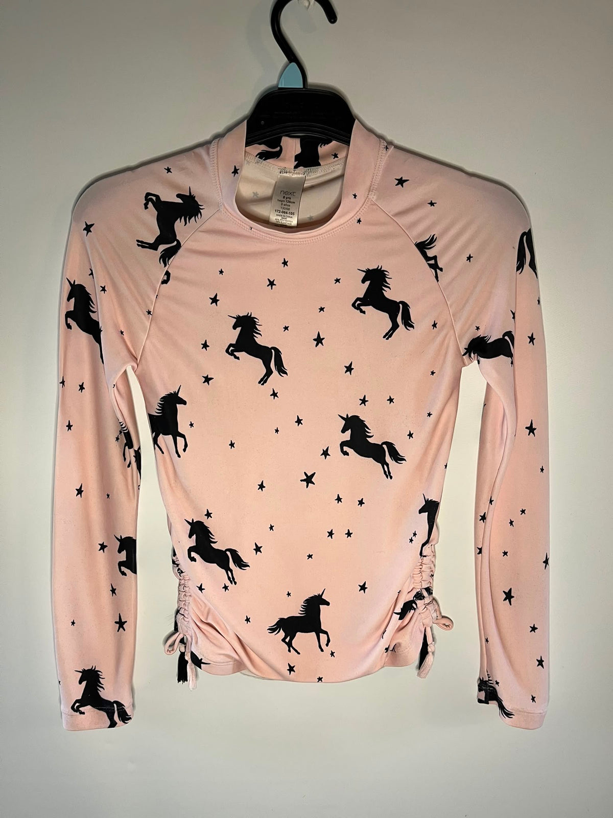 A light pink long-sleeve athletic top with a black unicorn and star print, next preloved size 8 years little drums