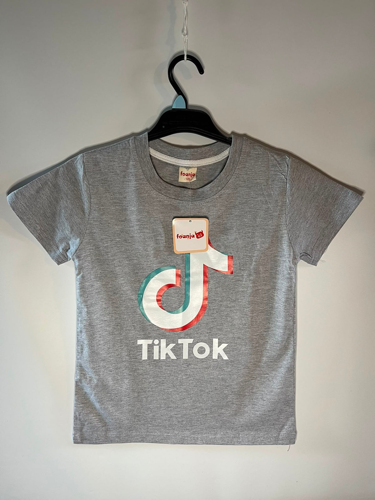 A heather gray short-sleeve T-shirt The shirt features a large TikTok logo graphic in white, red, and teal on the chest, with the word 'TikTok' printed below in white. Preloved little drums
