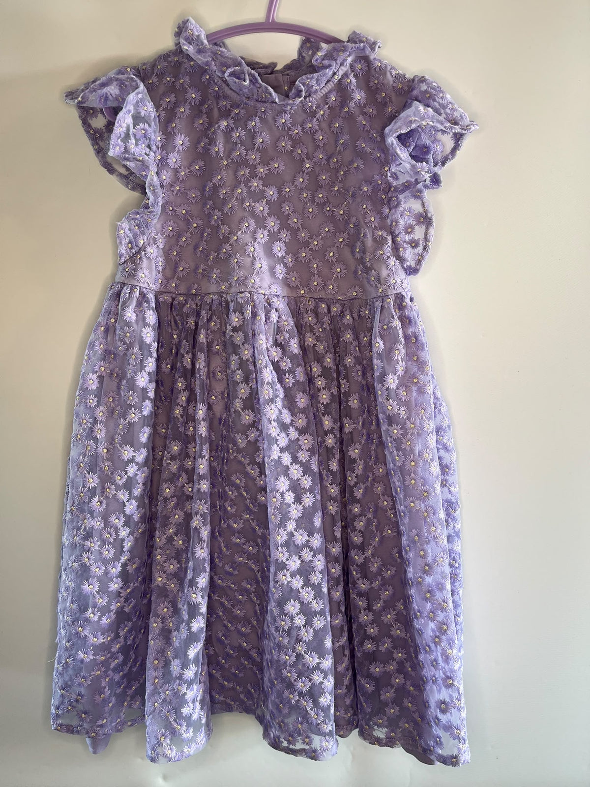 A lavender purple babydoll dress with a white floral lace pattern, featuring ruffled short sleeves and a ruffled neckline,