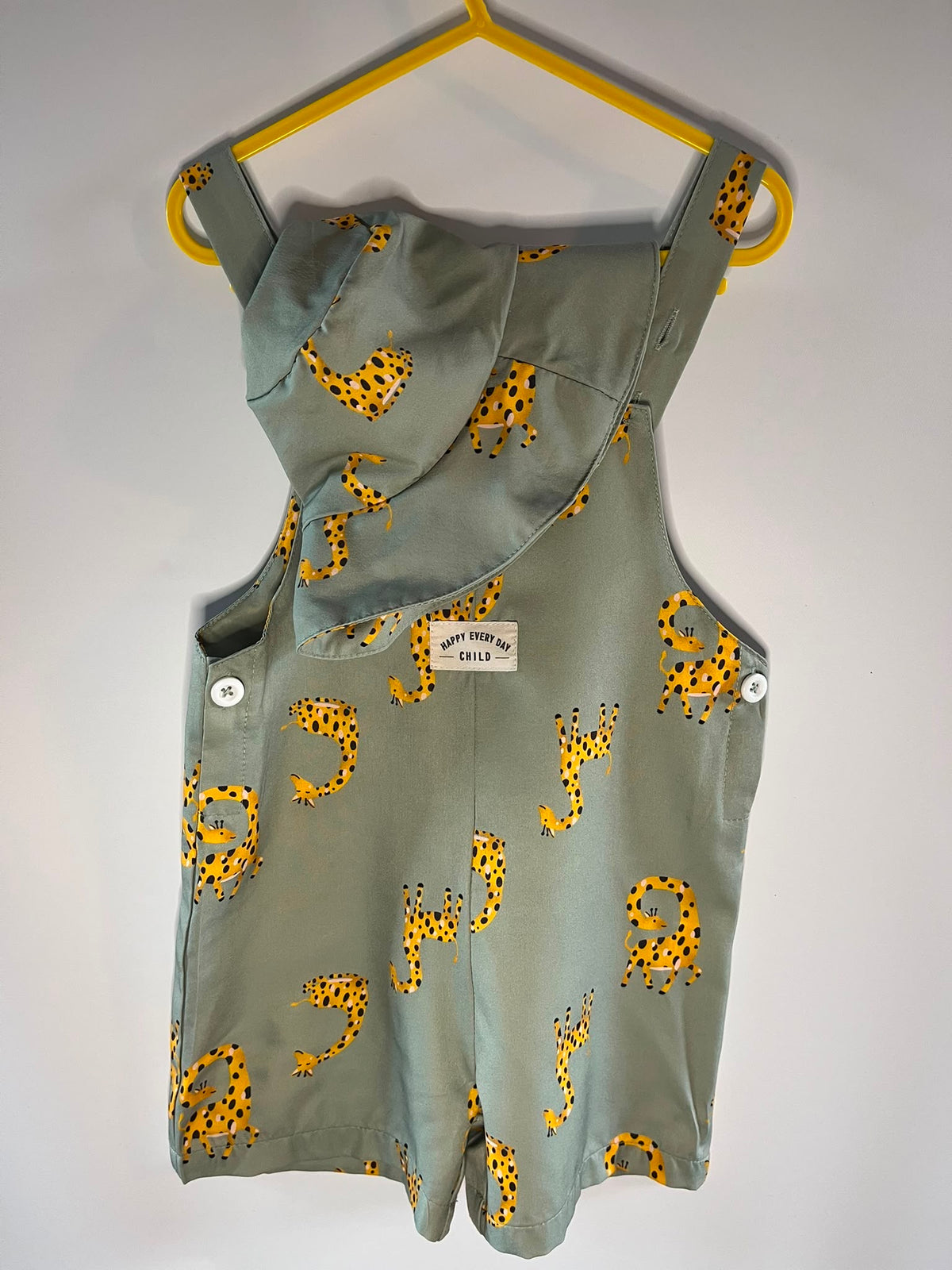 A sage green sleeveless romper with a yellow and black giraffe print, SHEIN preloved