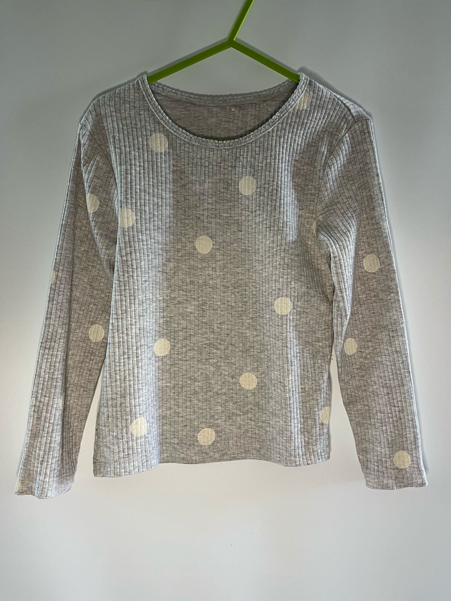 Gray long-sleeve shirt with white polka dots on a hanger against a plain background
