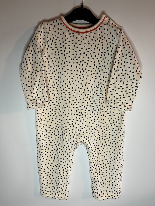 Baby onesie with black polka dots on a hanger against a white background. Preloved little drums - John Lewis size 9-12 months 