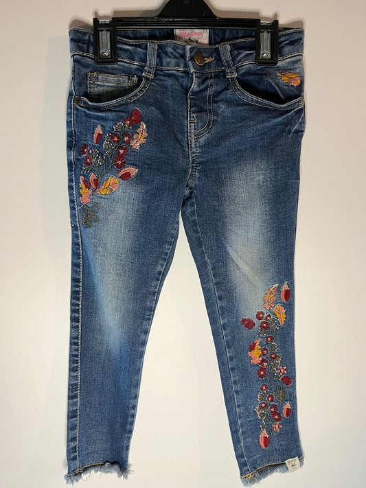 Blue jeans with floral embroidery on a white background, preloved little drums