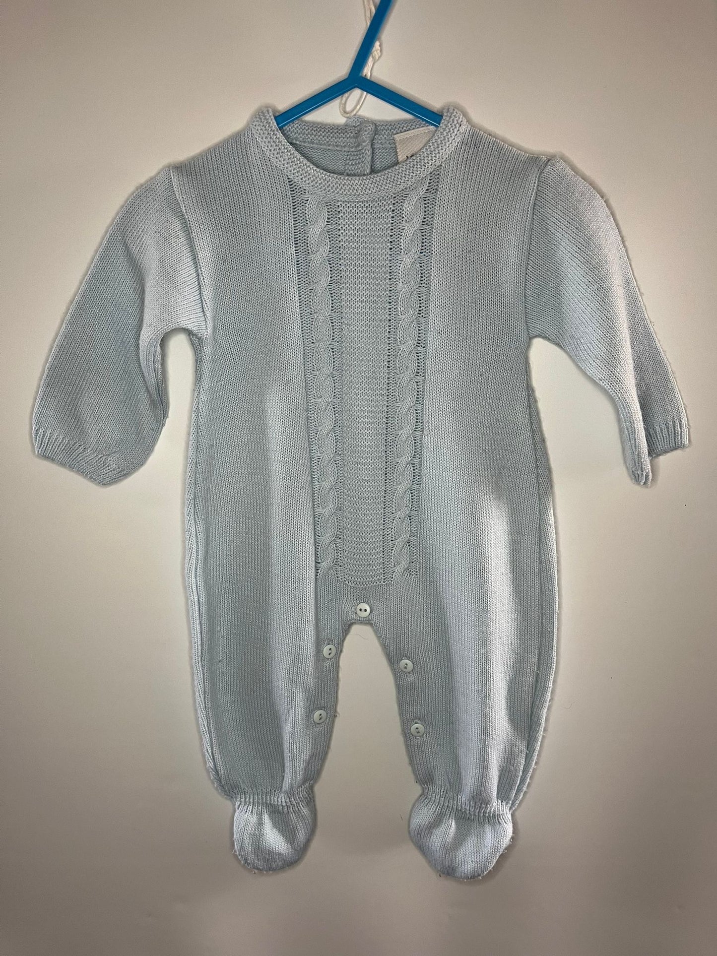 Gray knitted baby romper on a hanger against a beige background