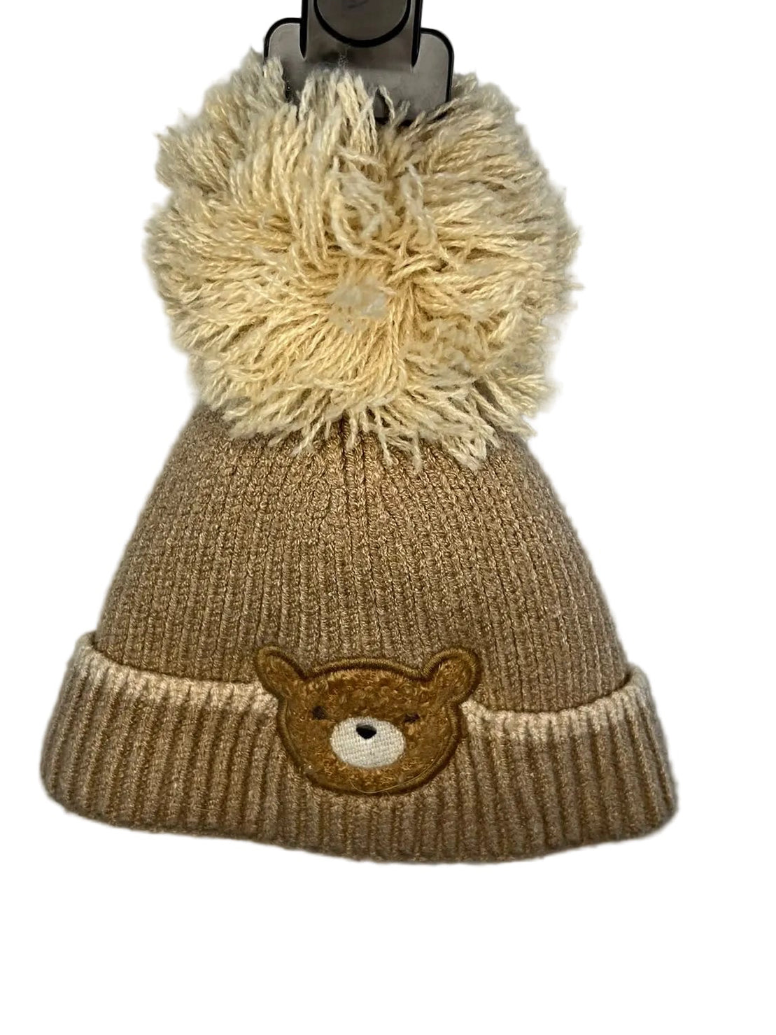 A beige knit beanie hat with a large cream pom-pom on top and a small embroidered teddy bear face on the front cuff,preloved little drums 