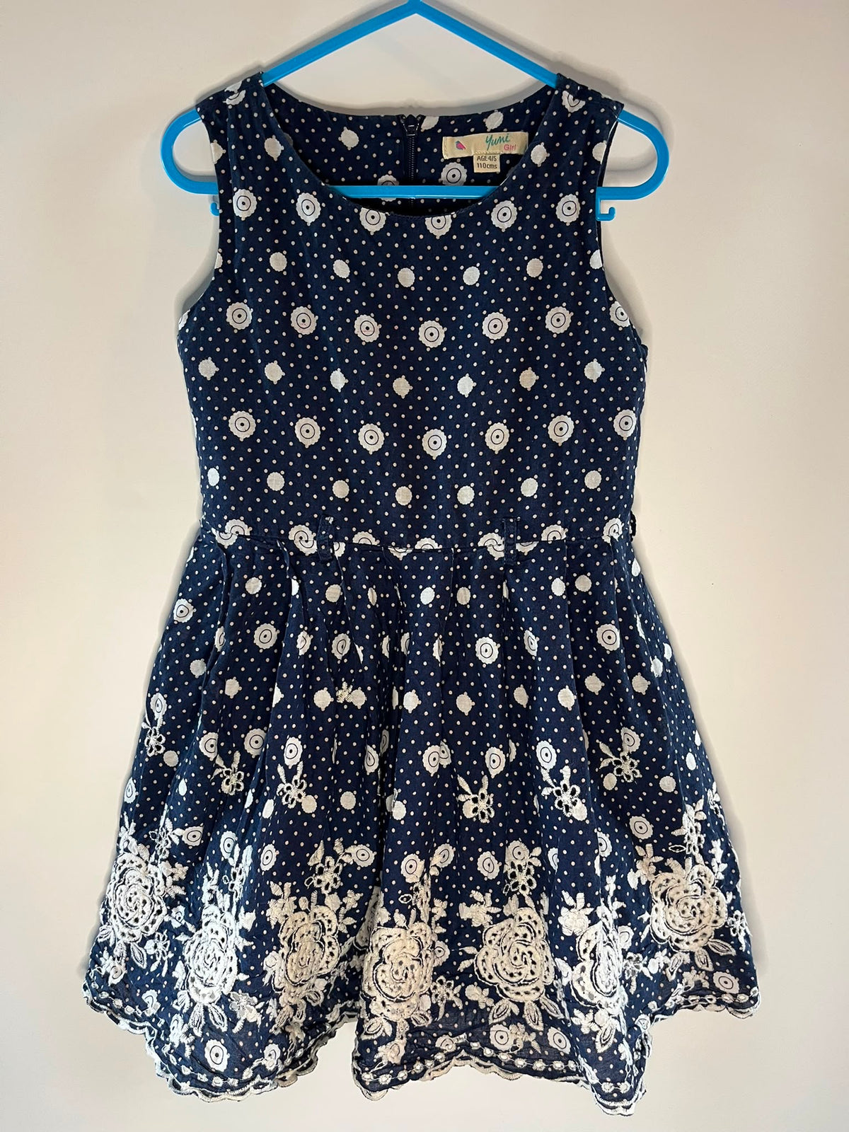 A sleeveless navy blue dress with white polka dots and floral lace applique, Yumi girl preloved little drums 