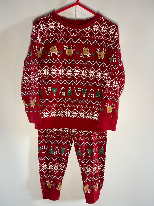 A red Christmas-themed matching sweatshirt and jogger pants set.. The long-sleeve top and pants feature white snowflake and geometric patterns, green pine trees, and gold reindeer motifs.