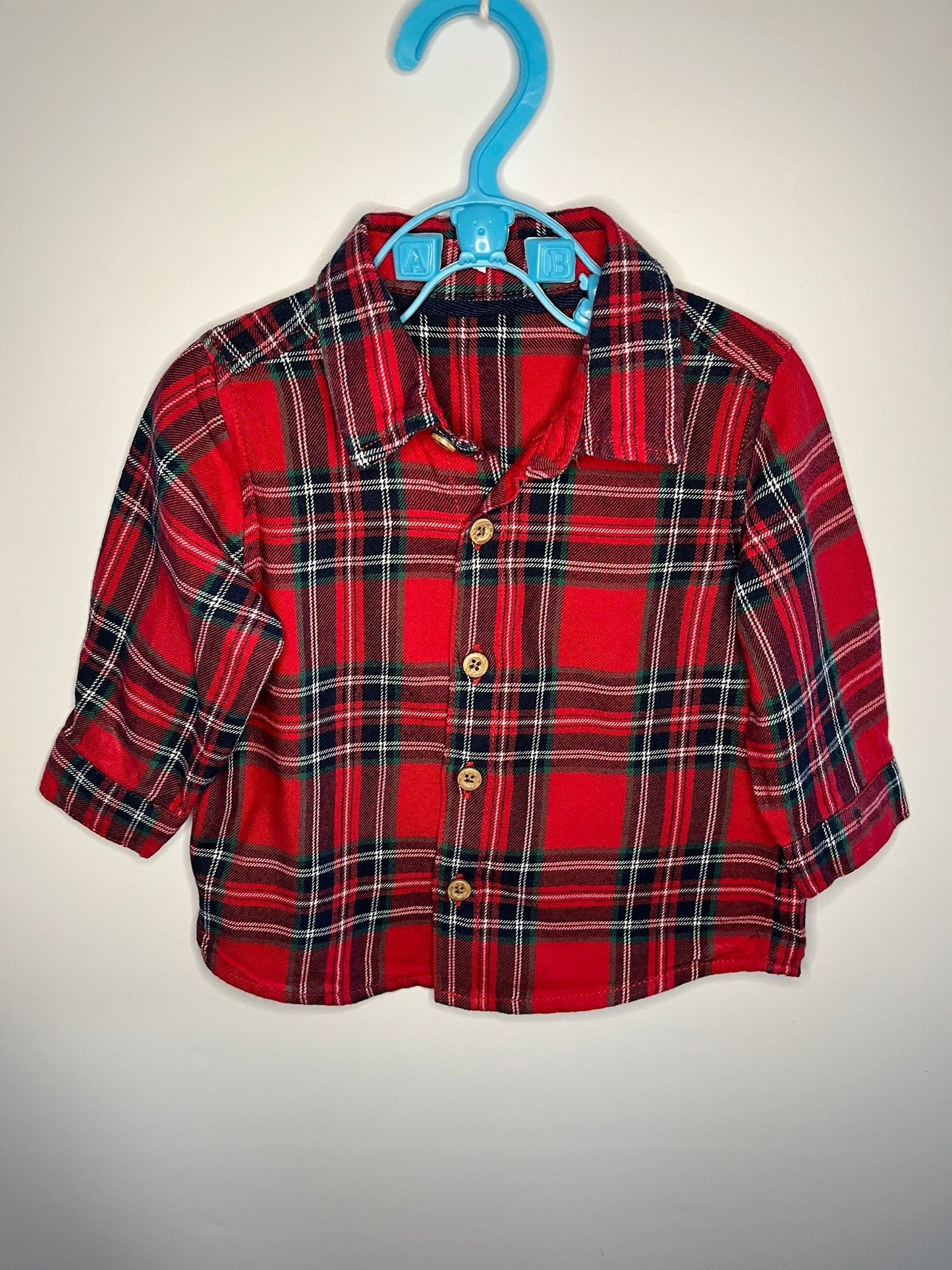 Red plaid shirt on a blue hanger against a white background little drums preloved 