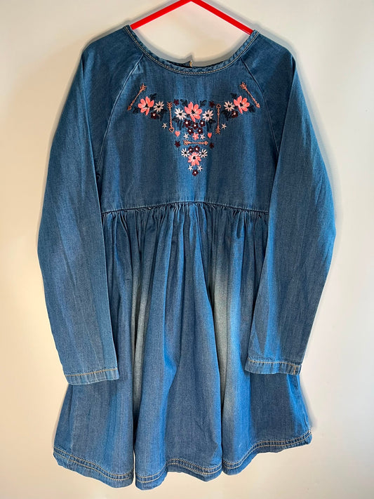 A blue denim long-sleeve dress with a gathered waist and colorful floral embroidery on the chest, mothercare preloved little drums size 6-7 years 