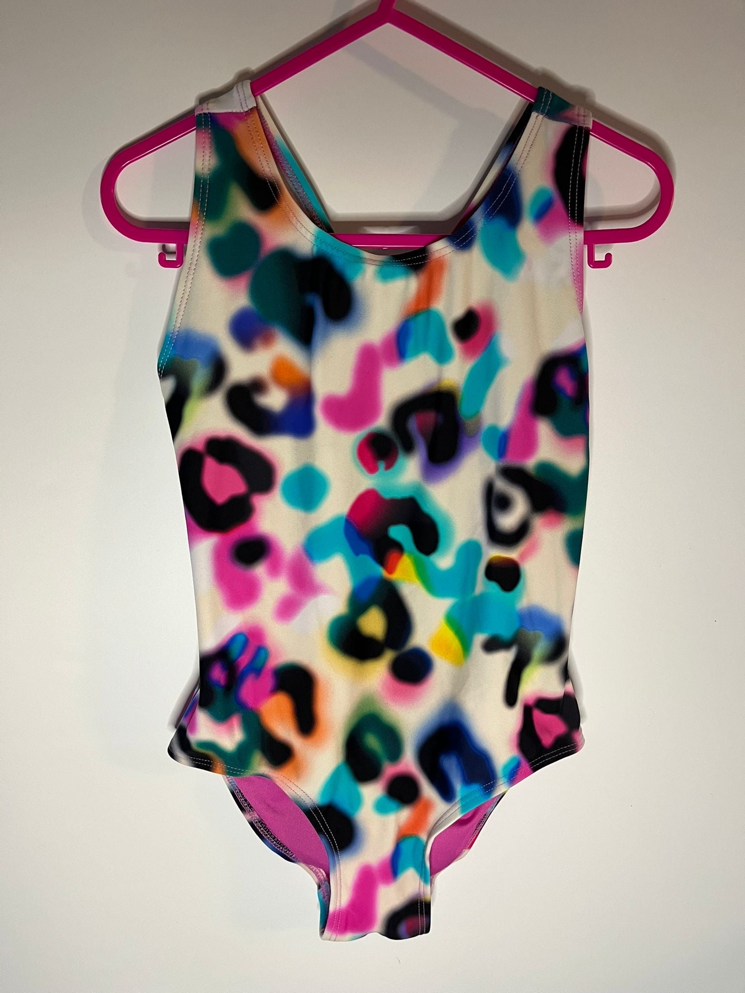 Colorful leopard print swimsuit on a pink hanger against a white background