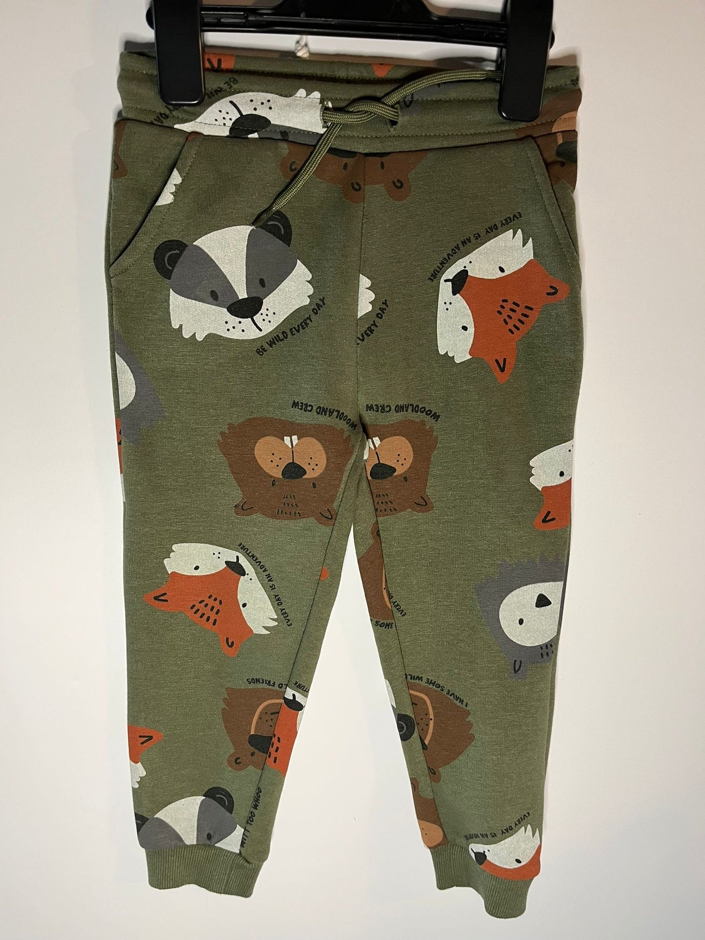 Green children's pants with animal pattern on a white background