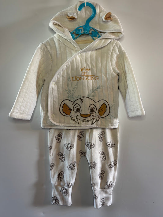 A baby two-piece pajama set featuring a hooded long-sleeve top and matching pants, both in a cream-colored ribbed fabric. The top is decorated with an embroidered Simba face and 'SABO THE LION KING' text, while the pants are patterned with small Simba faces.