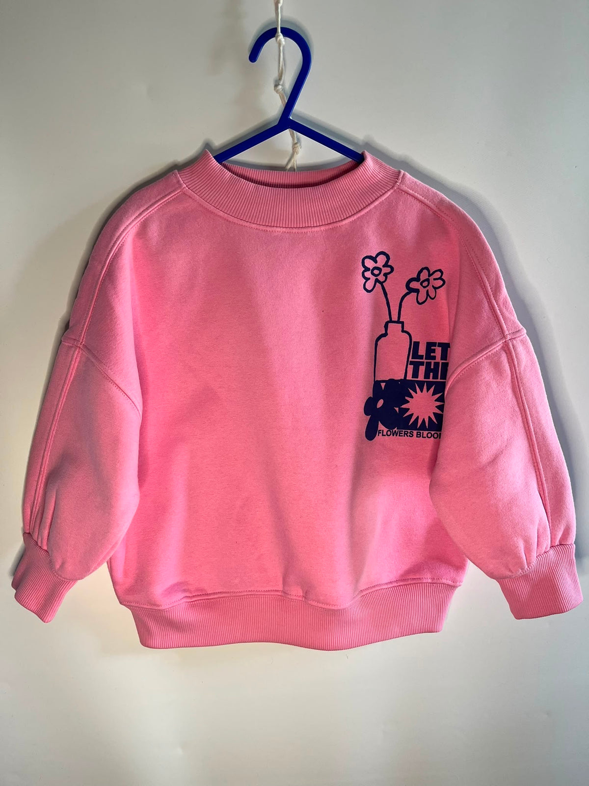 A pink crewneck sweatshirt with a dark navy graphic on the left chest featuring flowers, a bottle, and the text 'LET THIN' and 'WATER BOTTLE', next preloved little drums size 4-5 years 