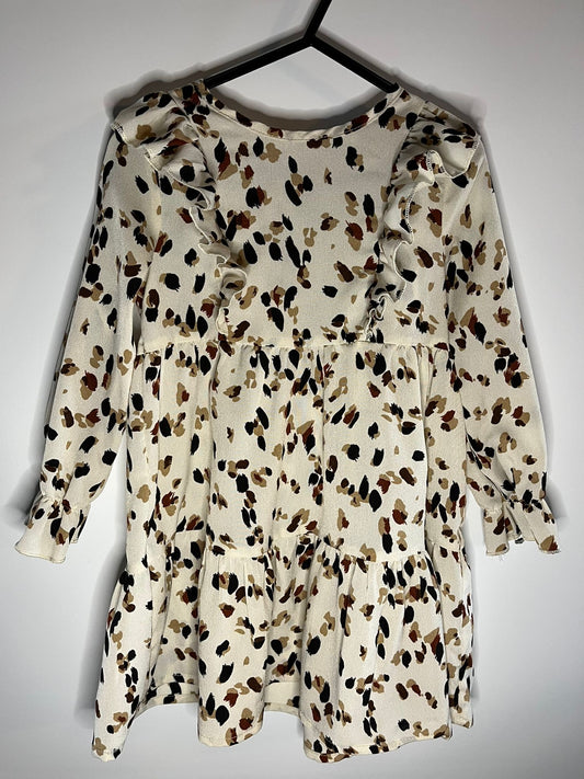 White dress with brown and black speckled pattern on a hanger against a white background