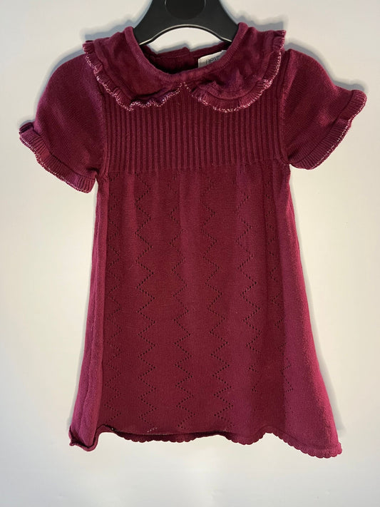 Maroon knitted dress with ruffled collar on a hanger against a white background