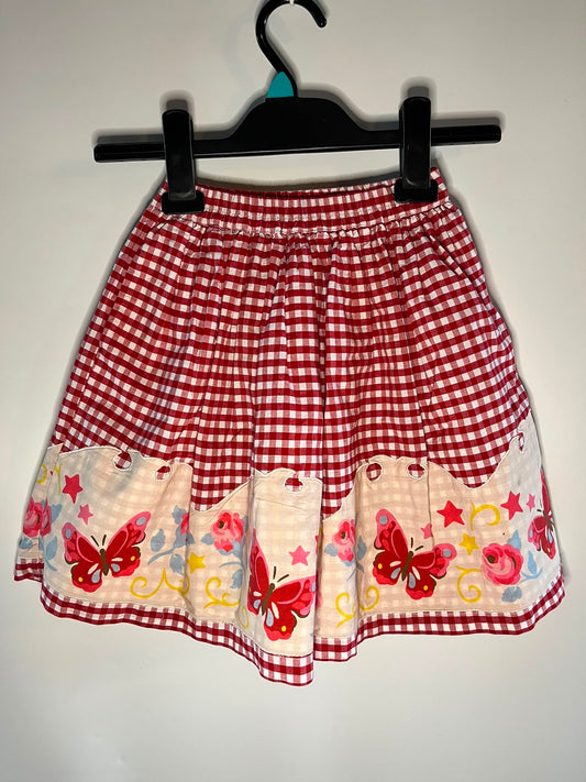 A red and white gingham skirt with a decorative ruffled hem featuring embroidered red butterflies, pink flowers, and yellow stars on a cream background, cath Kidson size 4-5 years preloved little drums 