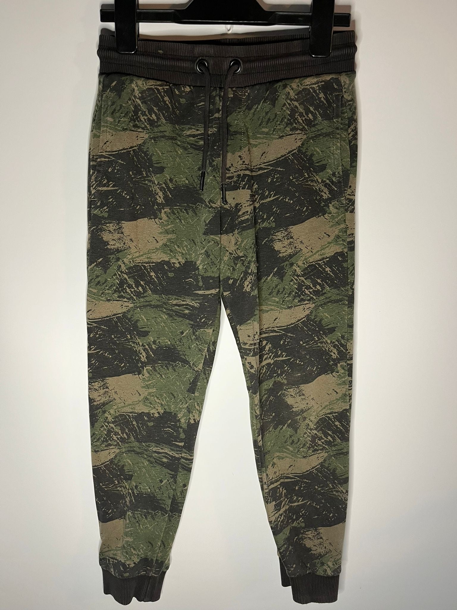 Camouflage pants on a hanger against a white background. F&F jogger bottoms, preloved little drums 